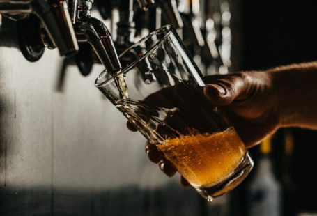 Craft Beer - person pouring brown liquid on clear drinking glass