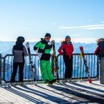 Ski Gear - people in green jacket and blue pants standing on ice field during daytime