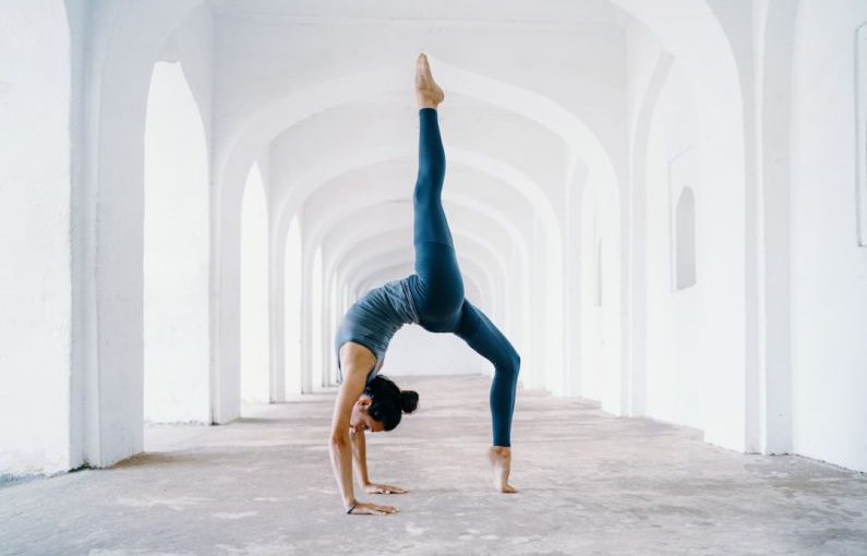 Yoga Pose - woman in blue leggings and black tank top doing yoga