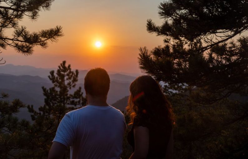 Romantic View - a man and woman kissing in front of a sunset