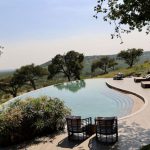 Luxury Lodge - a pool with a patio and chairs