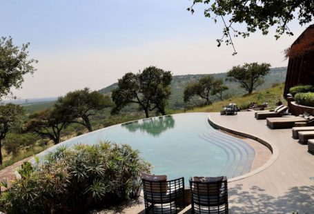 Luxury Lodge - a pool with a patio and chairs