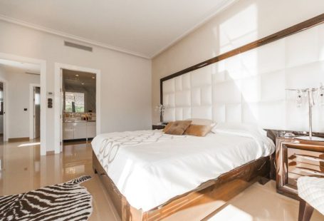 Hostel Room - brown wooden bed frame with white cover beside brown wooden nightstand