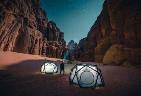 Camping - a man standing next to a tent in the desert