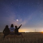 Star Gazing - three person sitting on grass during golden hour