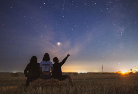 Star Gazing - three person sitting on grass during golden hour