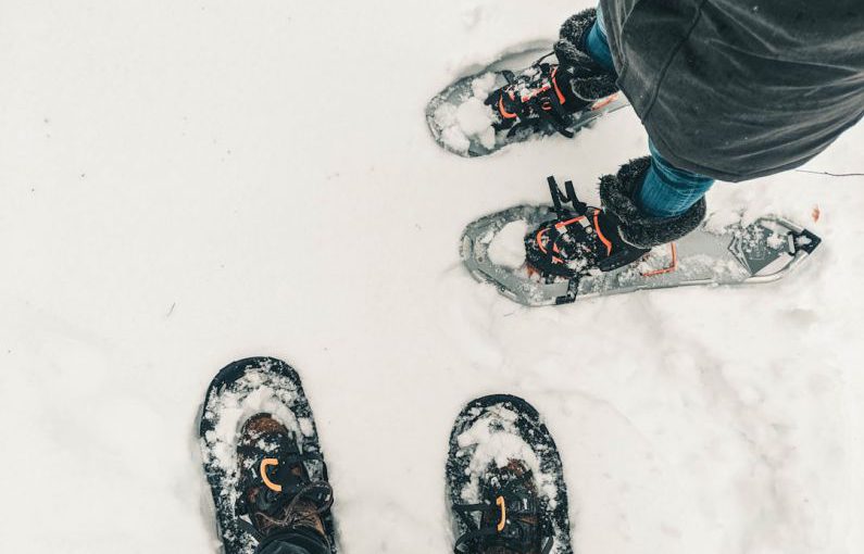 Snowshoeing - person in black pants and black and white snow ski shoes standing on snow covered ground