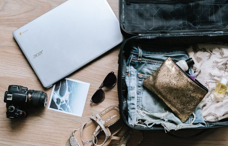 Suitcase - black DSLR camera near sunglasses and bag
