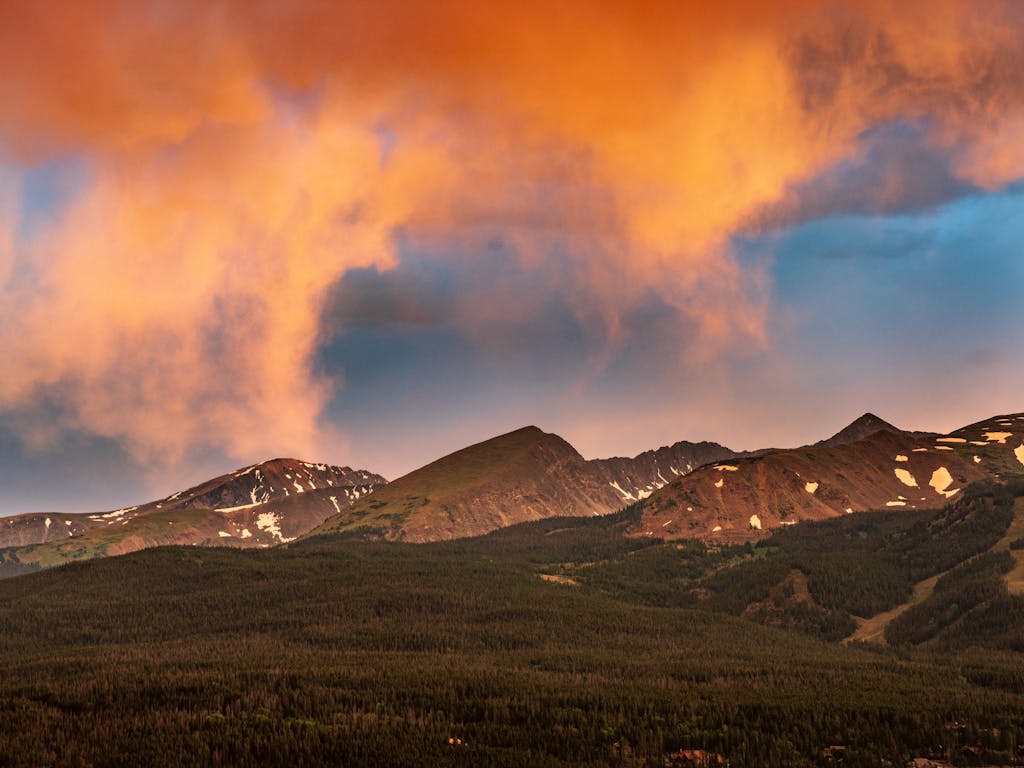 Stunning sunset over the mountains in Breckenridge, Colorado, showcasing vibrant clouds and scenic landscape.